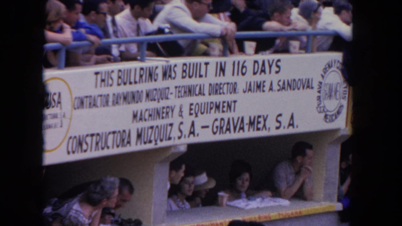 8mm color frame from a 1962 Los Angeles bullfighting event showing multi-tiered stands and a prominent white banner crediting Constructora Muzquiz S.A. and Grava-Mex S.A.