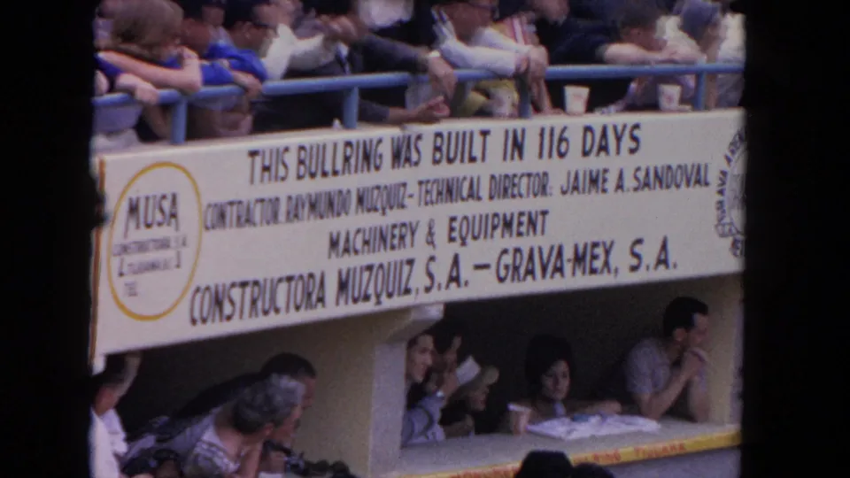 8mm color frame from a 1962 Los Angeles bullfight venue with the complete Constructora Muzquiz S.A. and Grava-Mex S.A. banner text clearly legible across the mid-frame.