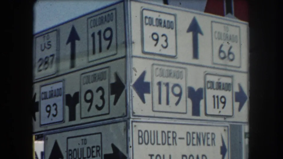 Close-up roadside signpost displaying Colorado routes 119, 93, 66, and US 287 with directional arrows; Boulder-Denver Toll Road sign partially visible at bottom, circa 1962 Summit County.