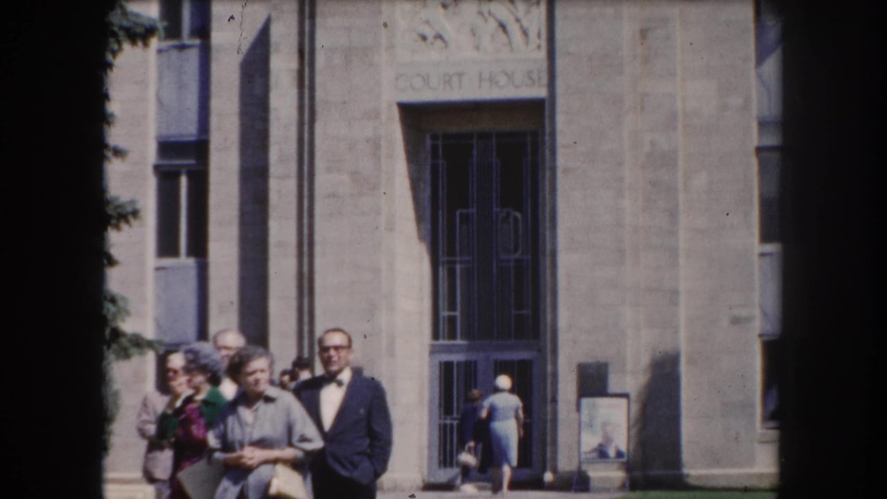 Adults in early-1960s attire grouped before a stone courthouse facade in what appears to be Summit County, Colorado, circa 1962.
