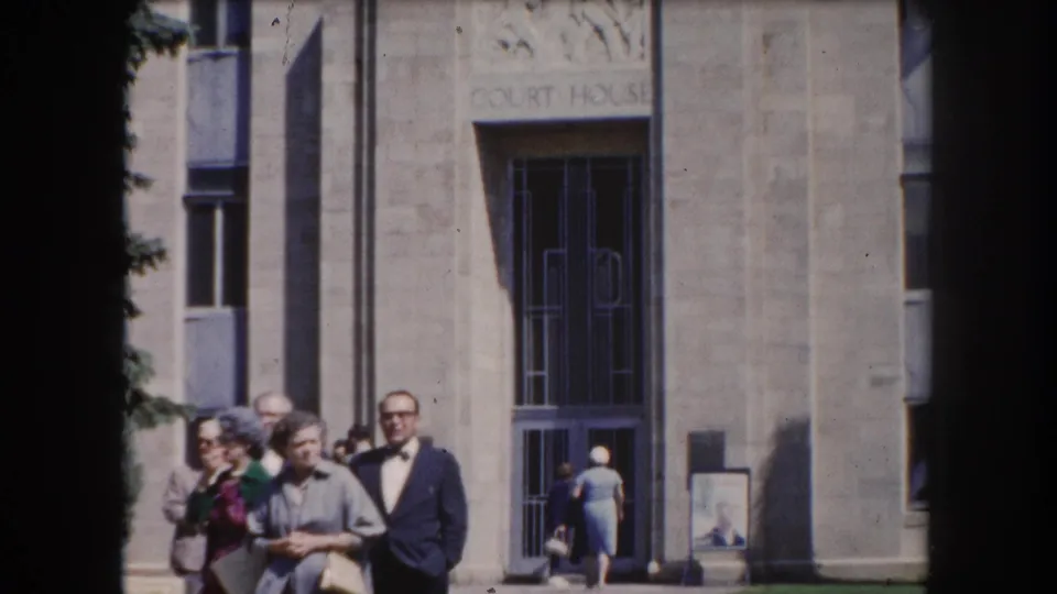 Adults in early-1960s attire grouped before a stone courthouse facade in what appears to be Summit County, Colorado, circa 1962.