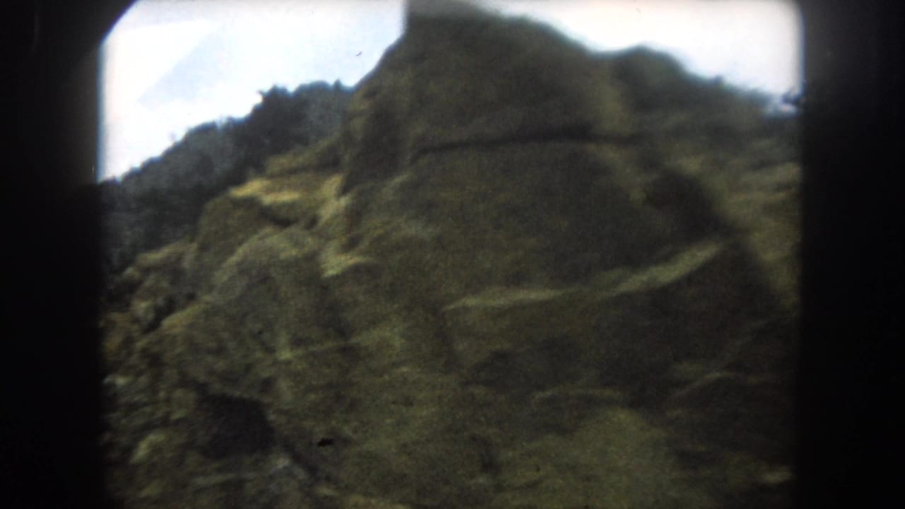8mm home movie frame showing a steep rocky mountain slope in close-up, consistent with Colorado high country, circa 1962.