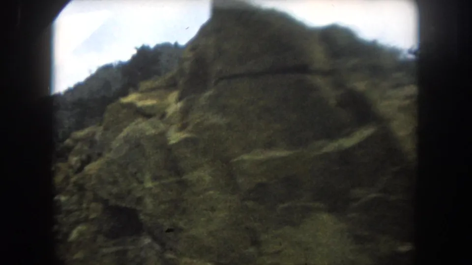 8mm home movie frame showing a steep rocky mountain slope in close-up, consistent with Colorado high country, circa 1962.