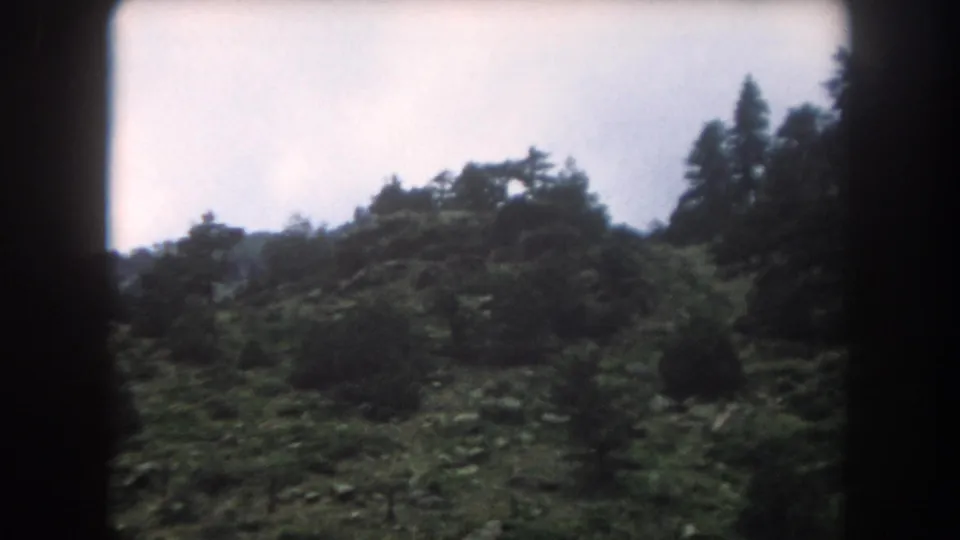 8mm home-movie frame circa 1962 showing a rocky ridge with scattered evergreens in Summit County, Colorado.