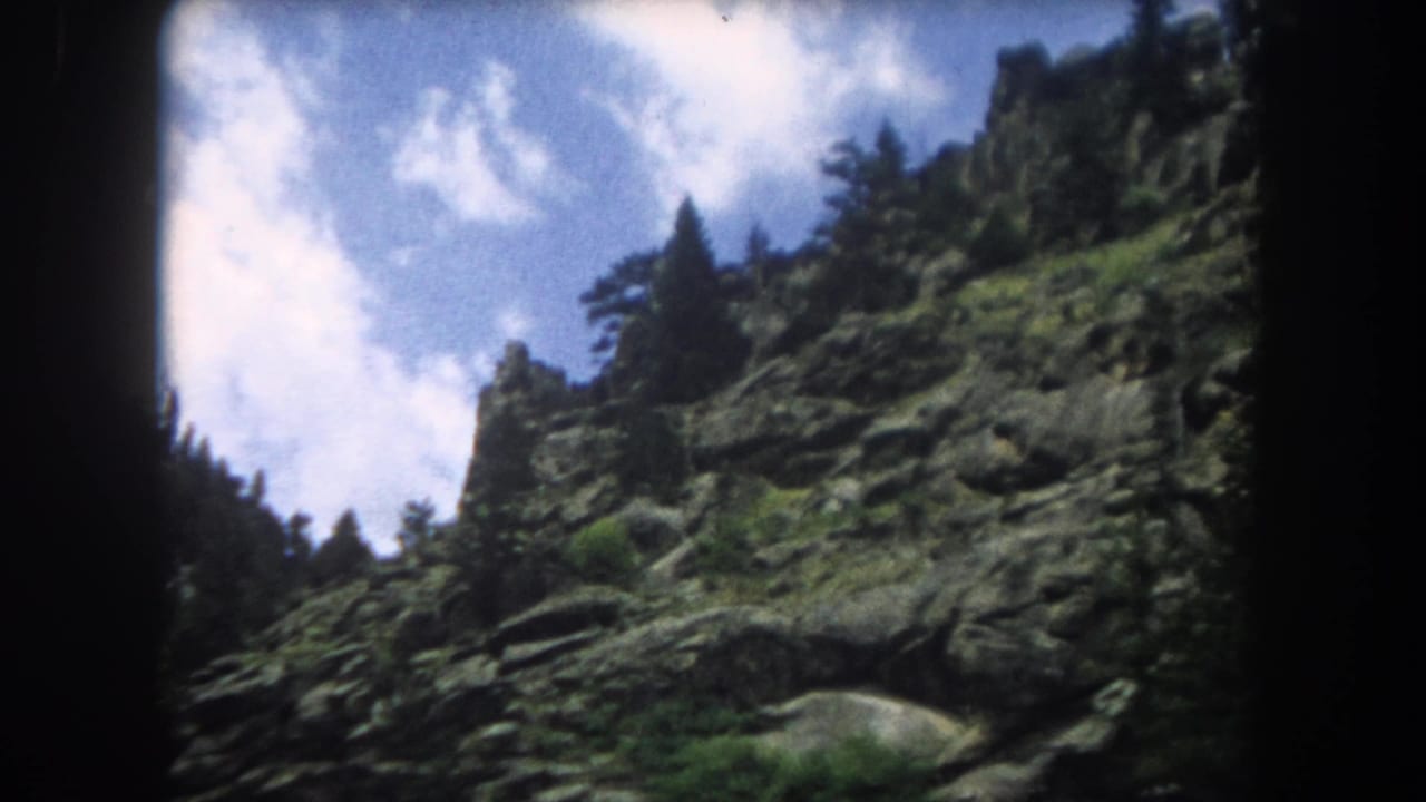 Continuation pan of a rugged Rocky Mountain slope in 8mm, consistent with 1962 Summit County Colorado footage