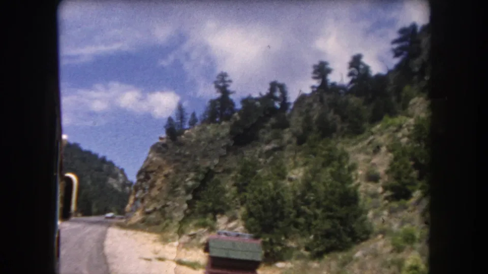 A curving dirt road through a Rocky Mountain canyon with dense evergreen forest, consistent with Summit County, Colorado, circa 1962.