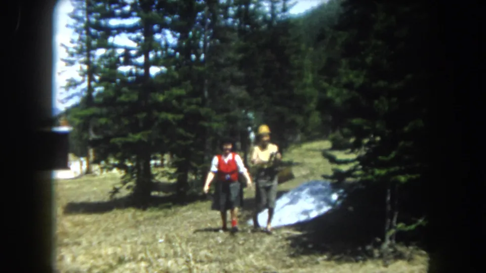 Two women in mid-century folk-style dress hold a large parabolic reflective dish toward the camera in a Rocky Mountain clearing, Summit County Colorado circa 1962.