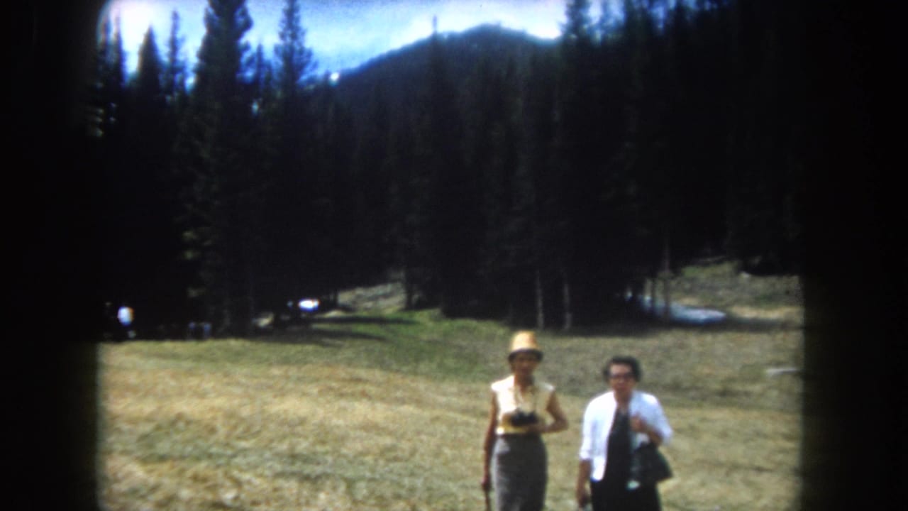 Two adult women in an open Rocky Mountain meadow, circa 1962; one in a straw hat, the other in a white top and dark skirt, filmed on 8mm.