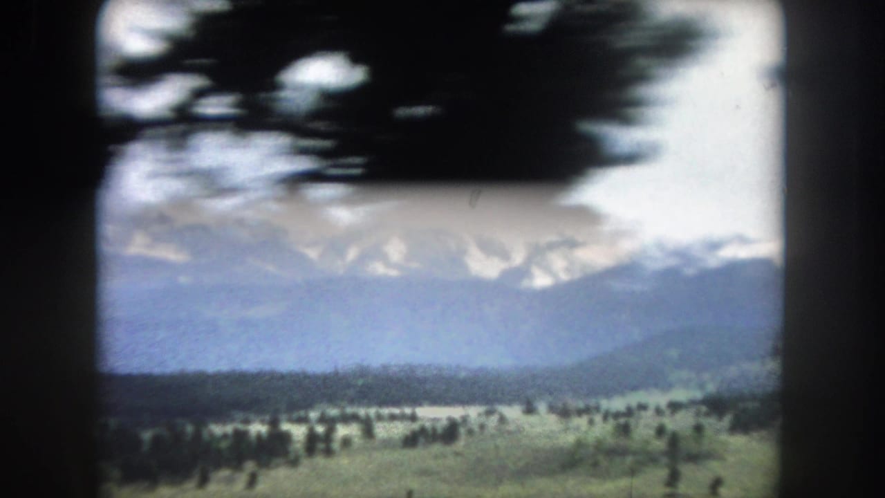 8mm home movie of snow-capped peaks above a wide open valley with scattered pines, Summit County, Colorado, circa 1962.