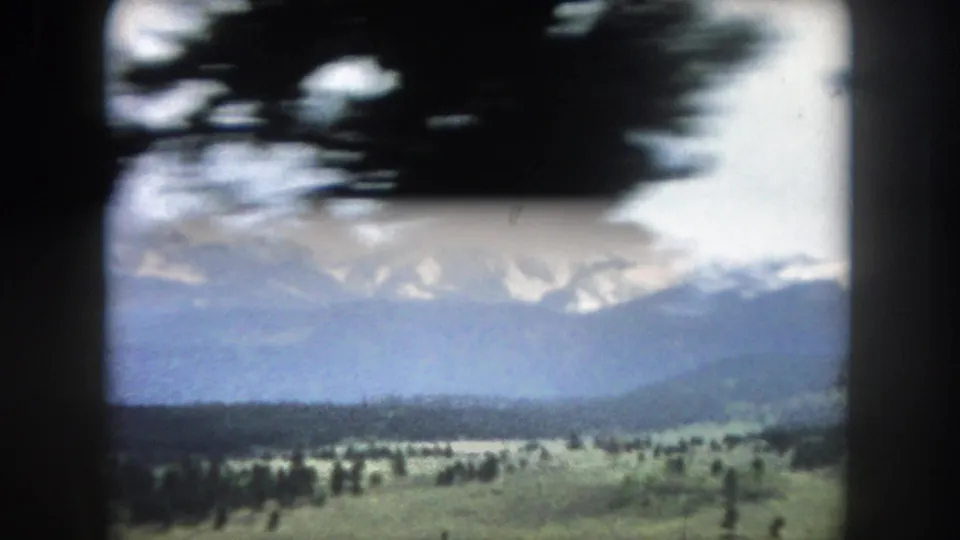 8mm home movie of snow-capped peaks above a wide open valley with scattered pines, Summit County, Colorado, circa 1962.