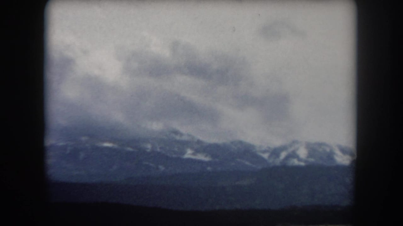 1962 Summit County, Colorado 8mm frame showing distant mountain ridges under a heavy gray sky.