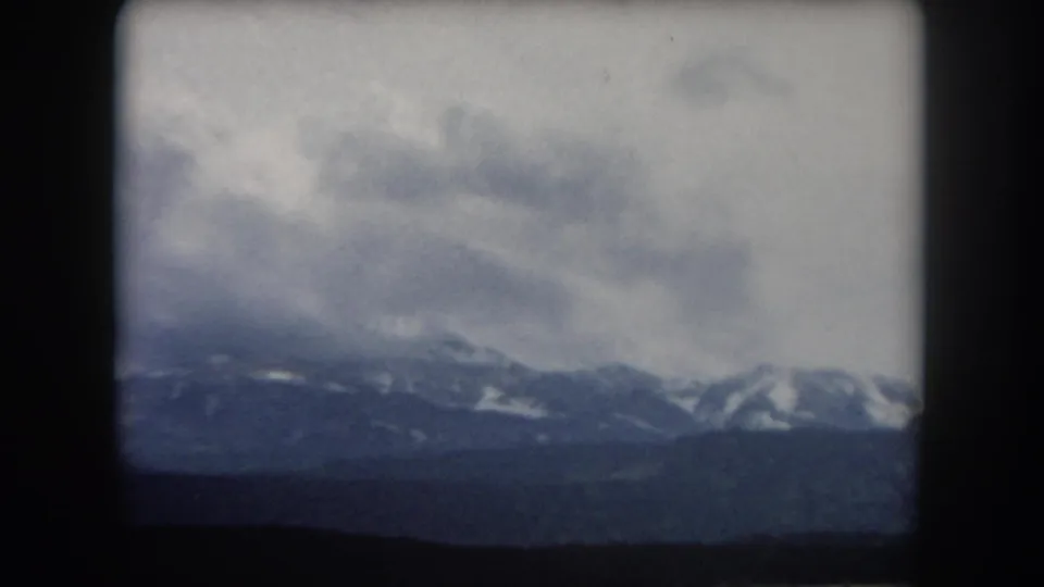 1962 Summit County, Colorado 8mm frame showing distant mountain ridges under a heavy gray sky.