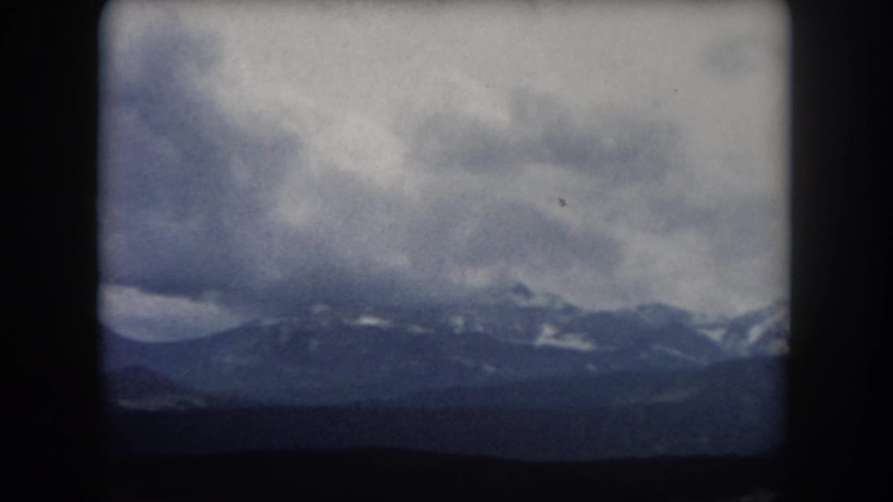 Cloudy mountain horizon with snow patches and dark lower foreground.