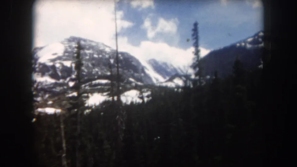 Summit County 8mm frame with snow-capped mountains, conifer forest, and visible small-gauge film borders.