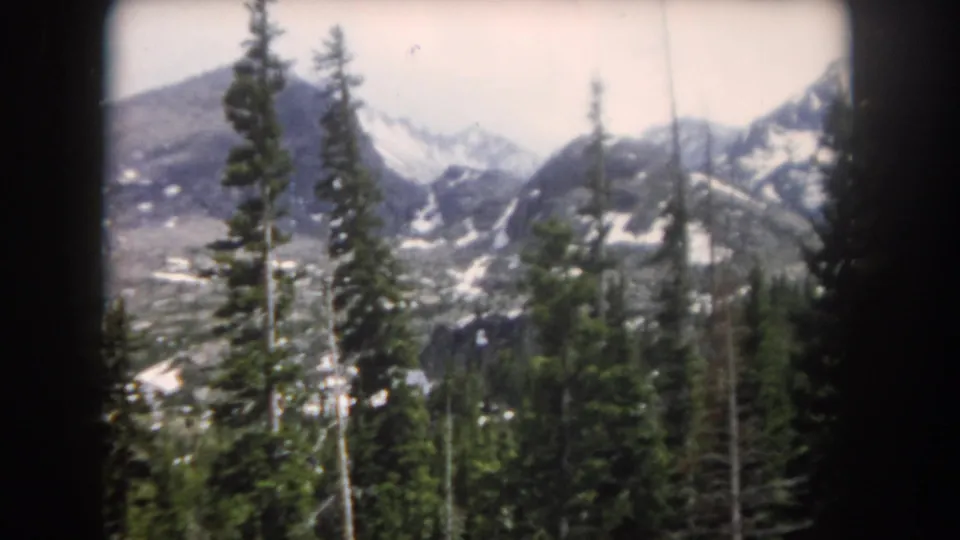 Snowy mountain slopes and tall conifers appear in this 1962 Summit County, Colorado 8mm home-movie frame.