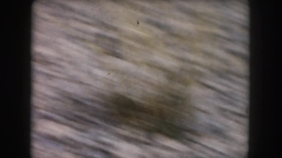 Soft, blurred 1962 8mm frame from Summit County, Colorado showing a rocky hillside in motion, likely before the animal settles in view.