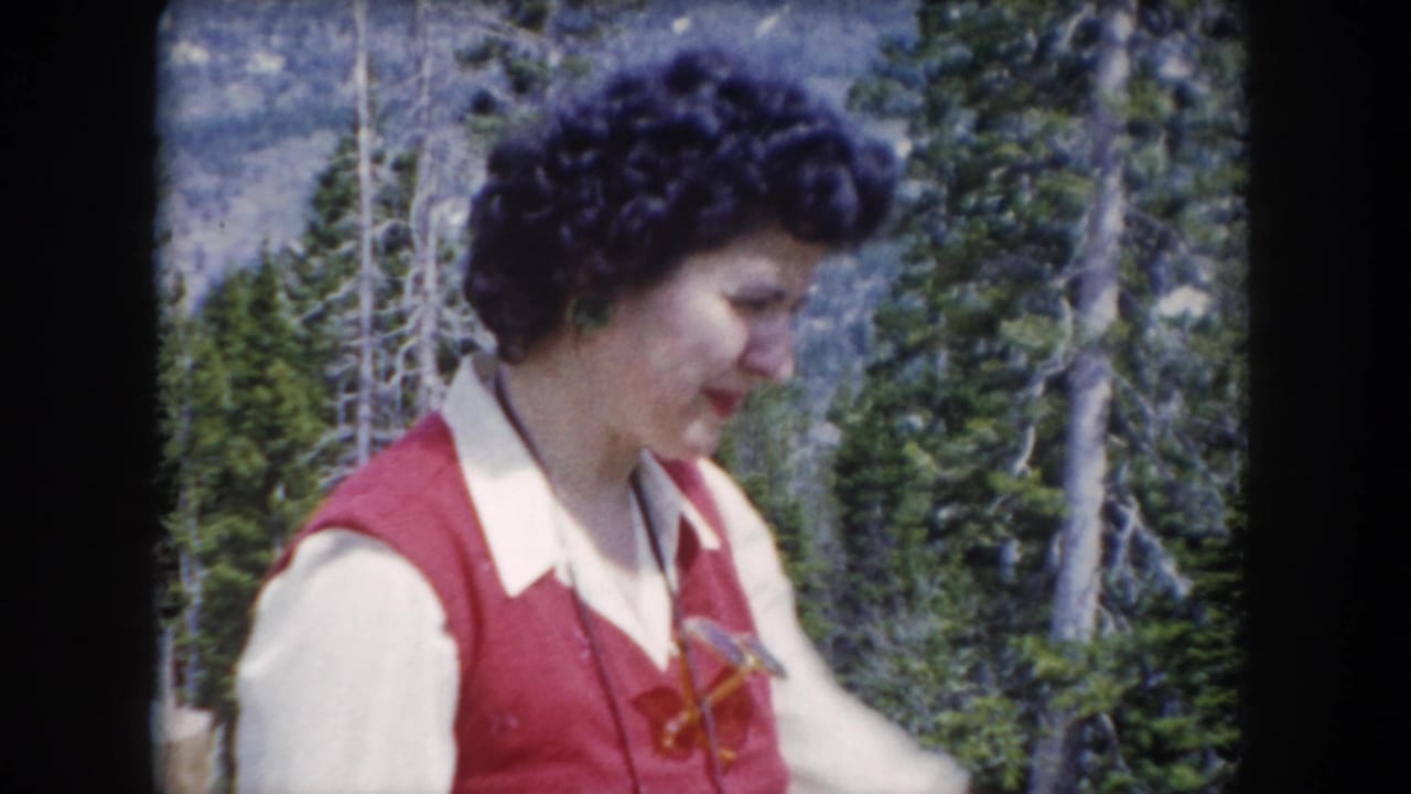 The woman appears in profile in 1962 Summit County, Colorado home-movie footage, standing before trees and rocky mountain terrain.