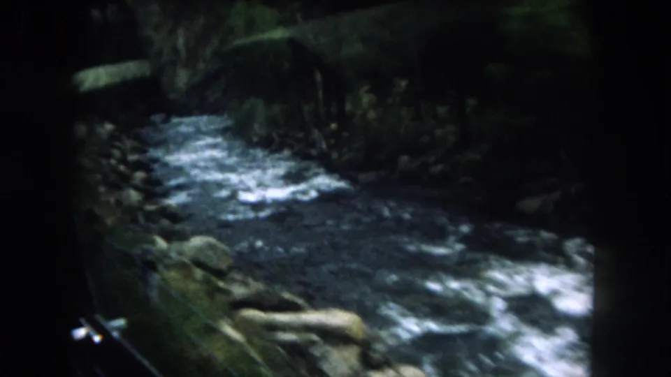 1962 Summit County, Colorado view of whitewater and rocky banks passing by from a moving vehicle window or side opening.