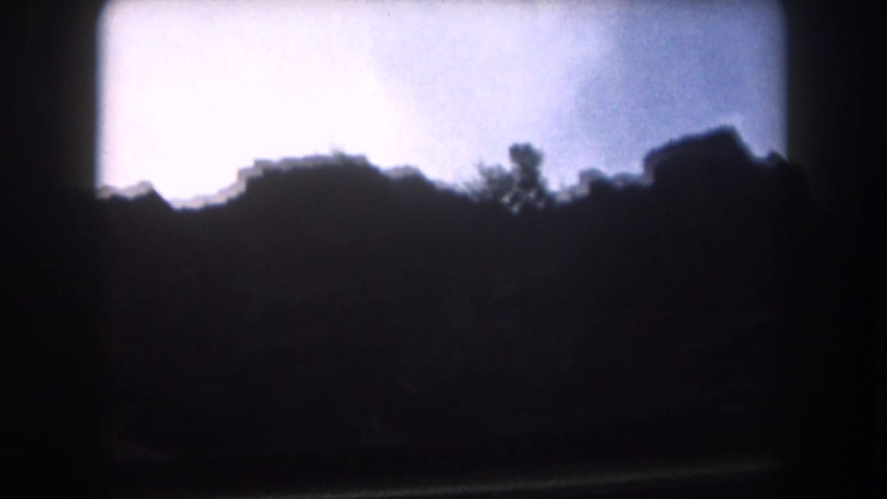 Silhouetted ridge and trees against a pale cloudy sky.