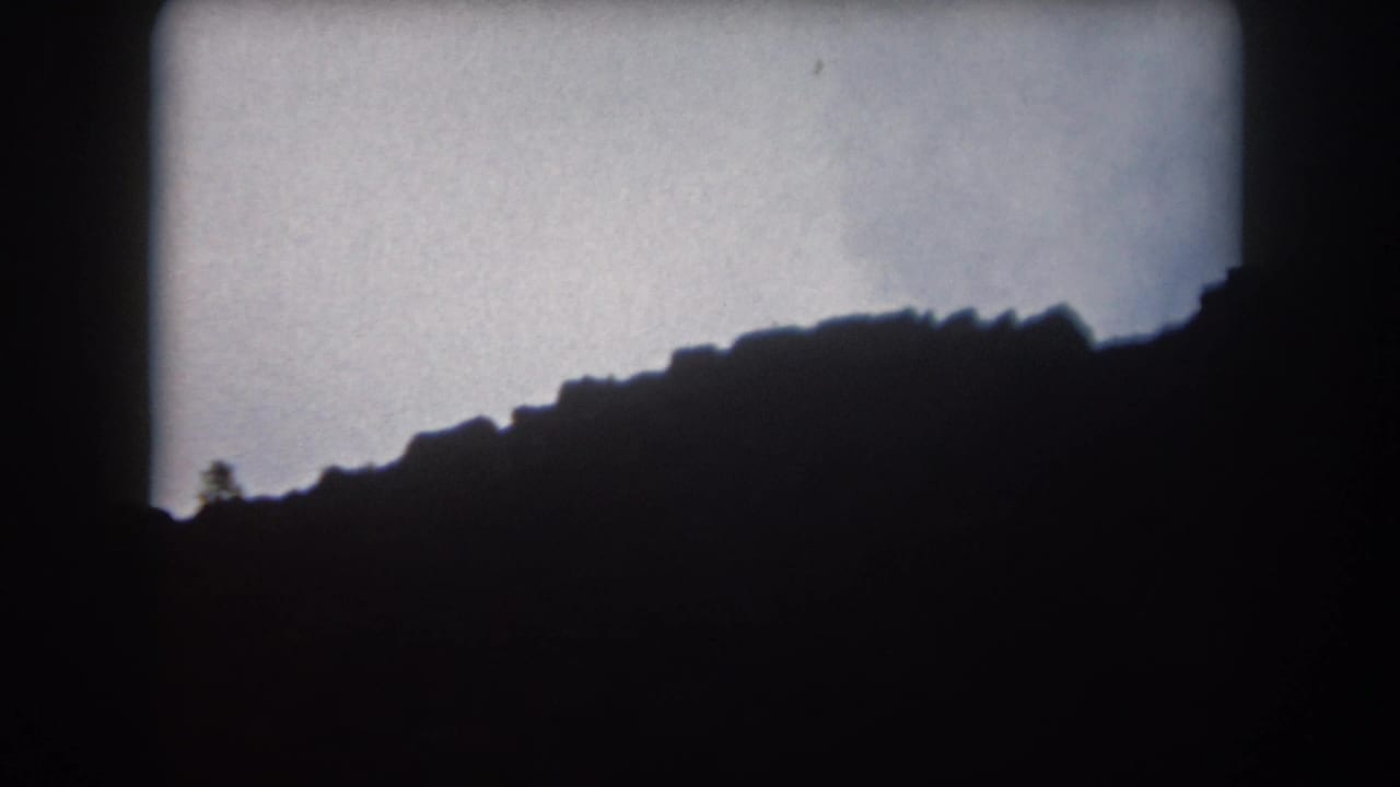 Dark mountain ridge silhouette beneath a pale dusk sky with rounded 8mm frame edges.