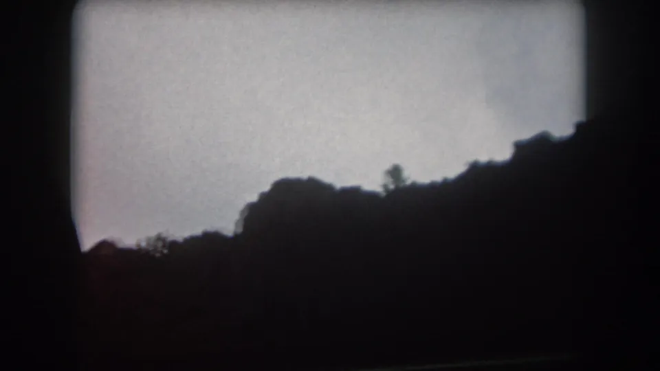Summit County, Colorado 8mm still from 1962 showing a low dark ridge, sparse tree silhouettes, and soft dusk exposure.