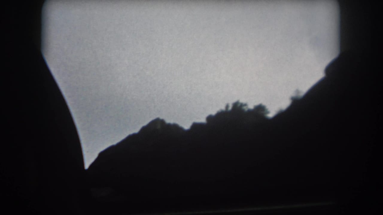 1962 Summit County, Colorado home-movie frame showing a silhouetted mountain ridge through a moving vehicle window.