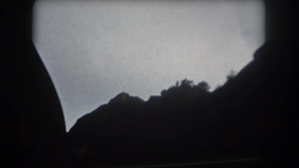 1962 Summit County, Colorado home-movie frame showing a silhouetted mountain ridge through a moving vehicle window.
