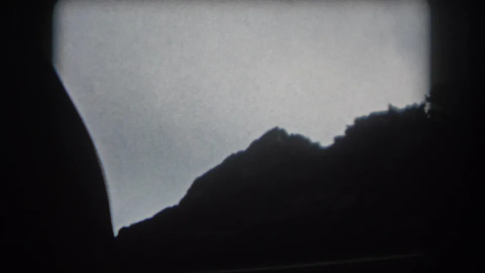 A moving-car view of Summit County mountain slopes, with the landscape reduced to dark silhouettes against the sky.