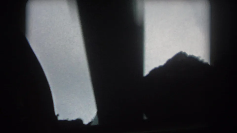 1962 8mm road footage with a mountain peak glimpsed between dark car-window or interior shapes in Summit County.
