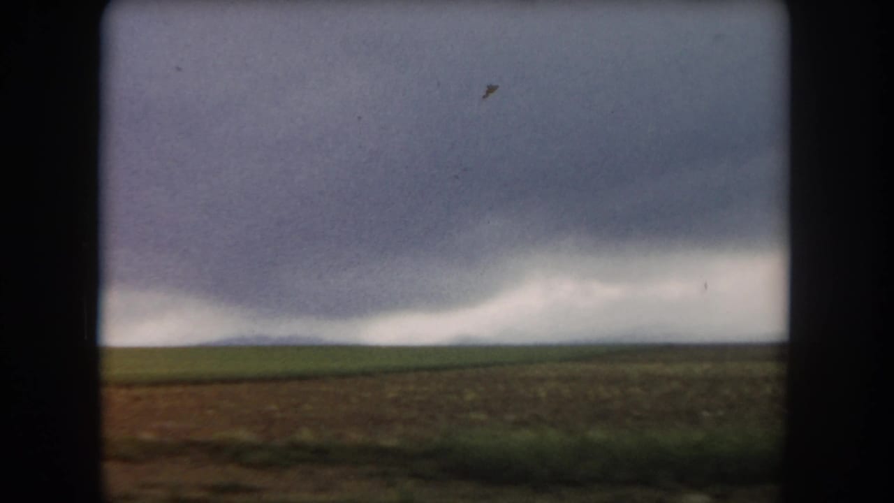 1962 Summit County, Colorado 8mm frame showing open fields beneath a heavy gray storm front on the horizon.