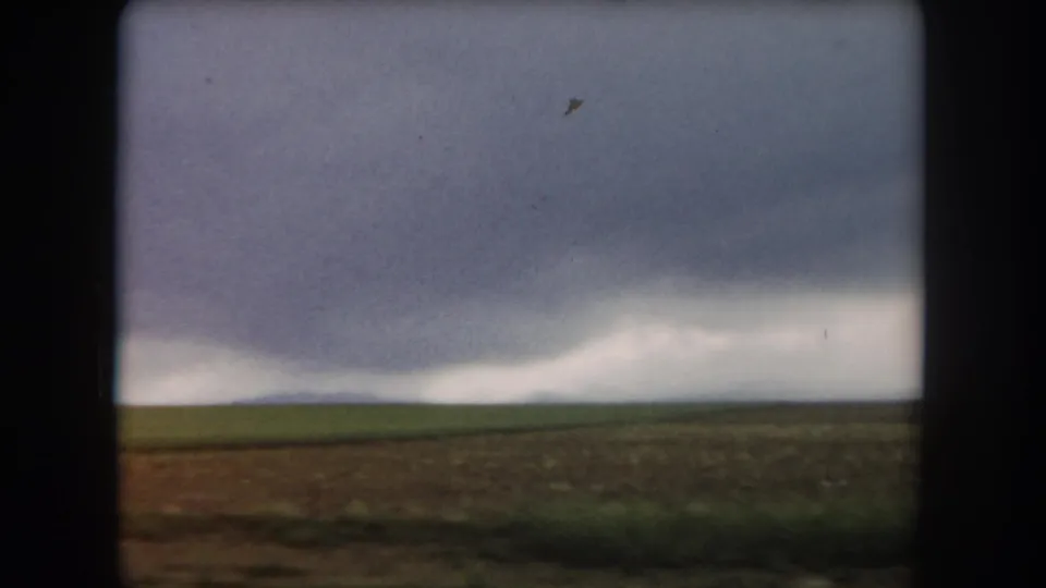 1962 Summit County, Colorado 8mm frame showing open fields beneath a heavy gray storm front on the horizon.