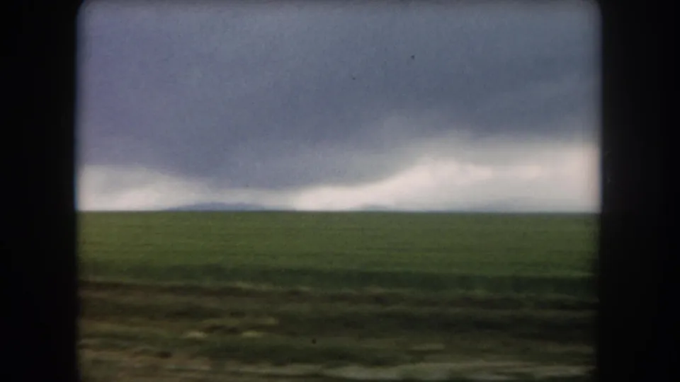 1962 Colorado 8mm frame showing open rural land and a distant dark weather system across the horizon.