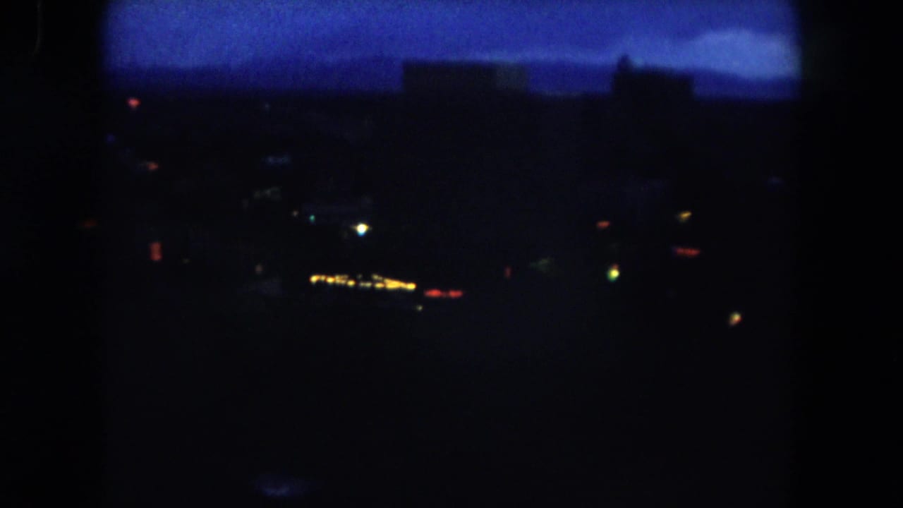 Dark 1962 Summit County twilight view with scattered town lights beneath a deep blue sky and silhouetted structures or hills.