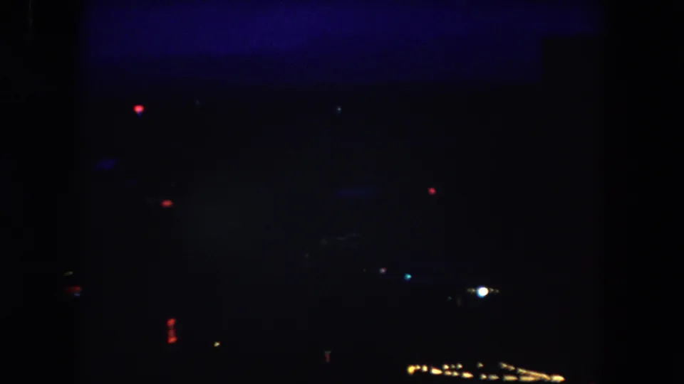 Final 8mm frame of the Summit County dusk view, with scattered colored lights and very dark silhouetted surroundings.