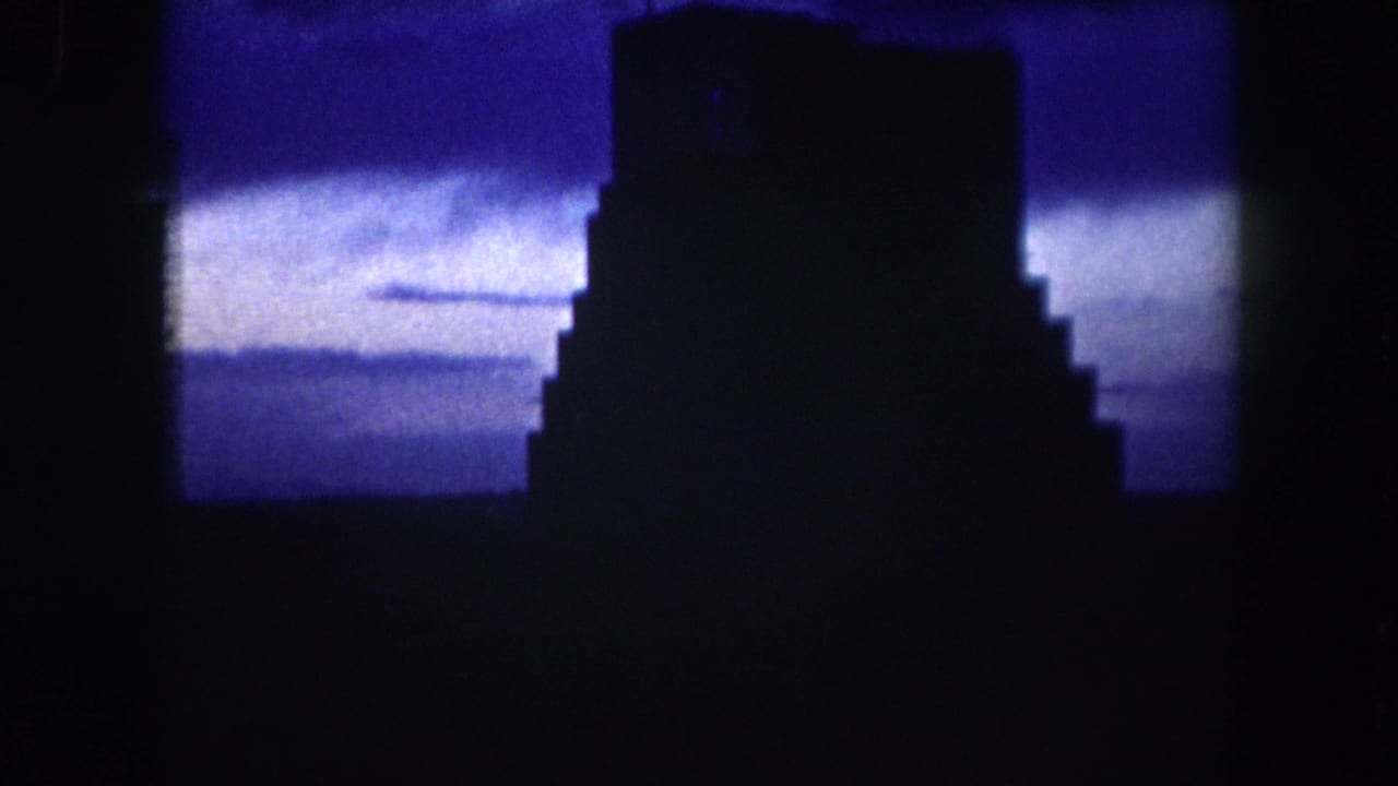 1962 Summit County 8mm frame showing a blocky building silhouette set against a deep blue evening sky.