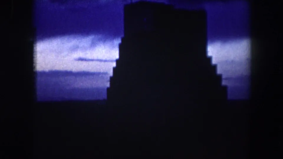 1962 Summit County 8mm frame showing a blocky building silhouette set against a deep blue evening sky.
