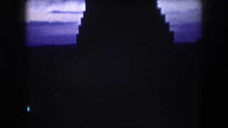 Final 1962 8mm frame showing the building nearly black against a blue twilight sky with one small light below.