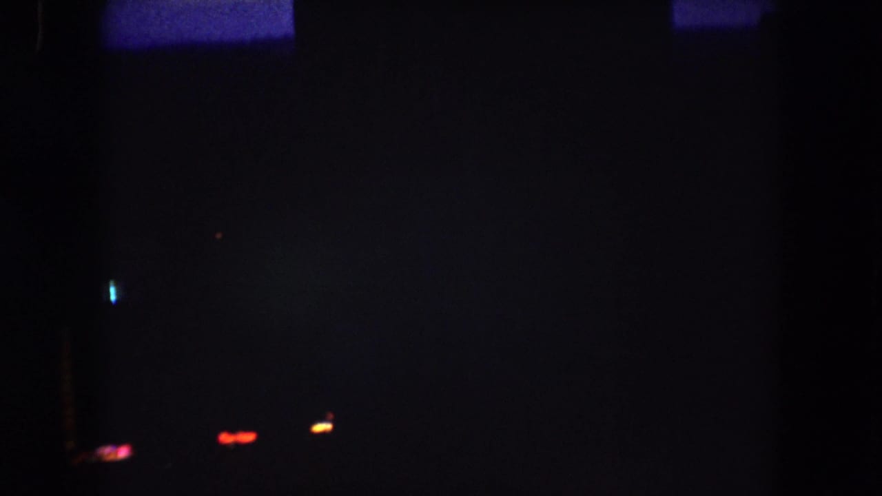 1962 Summit County night scene with dim silhouettes, scattered red and blue lights, and a vertical orange light pattern.