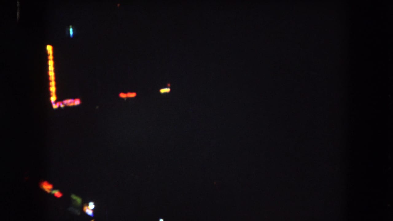 Very dark frame with a vertical orange light row and small colored light points.