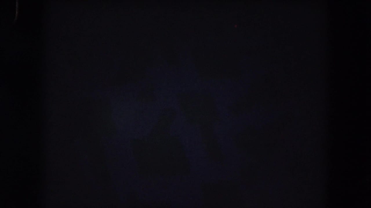 Mostly dark frame with faint blue film texture and little visible scene detail.