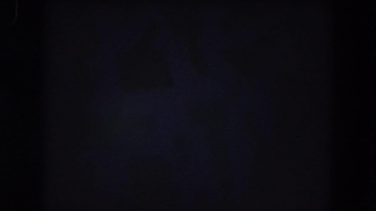 Dim 8mm frame with minimal visible detail, likely preceding the clearer crowd view in the 1962 Colorado home-movie clip.