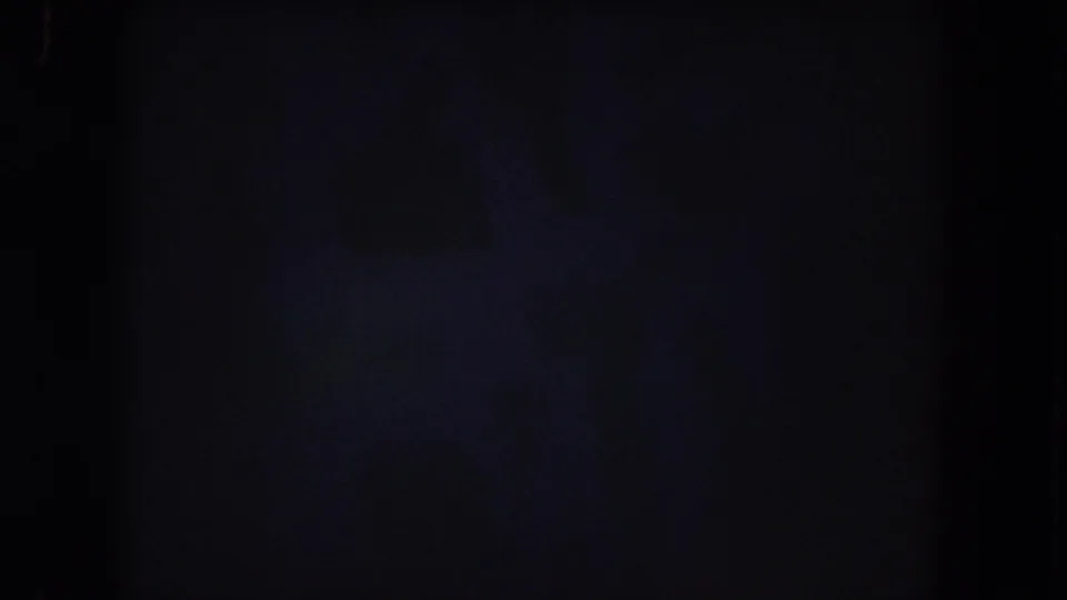 Dim 8mm frame with minimal visible detail, likely preceding the clearer crowd view in the 1962 Colorado home-movie clip.