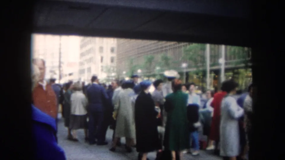 End frame showing a dense 1962 sidewalk crowd near a modern covered structure in Summit County, Colorado.