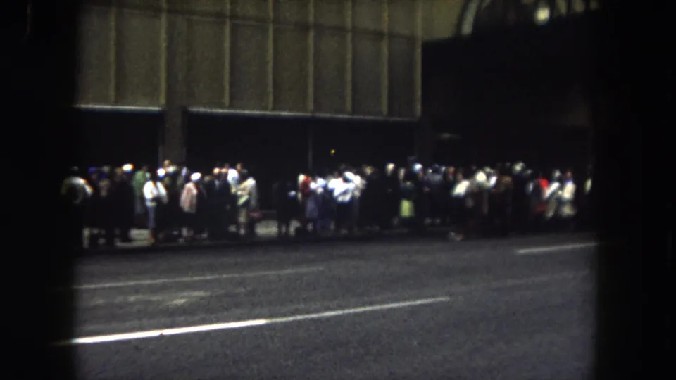 1962 Summit County, Colorado view of people gathered along a night street, filmed from across the road on 8mm.