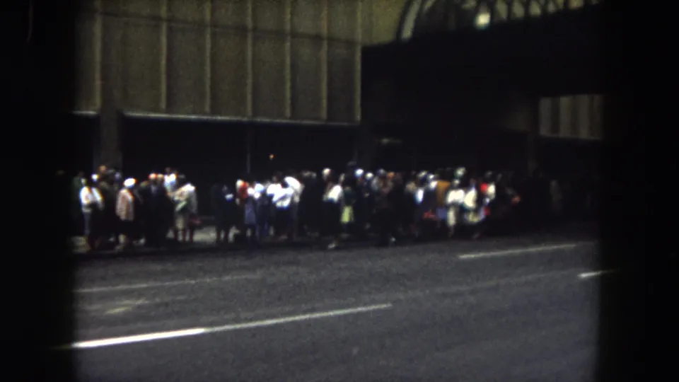 Archival 8mm frame from 1962 Summit County, Colorado showing a nighttime public gathering along a curb.