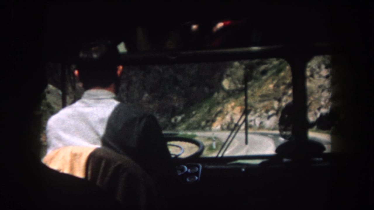 Backseat view of a man driving on a narrow mountain road in Summit County, Colorado, in 1962 home-movie footage.