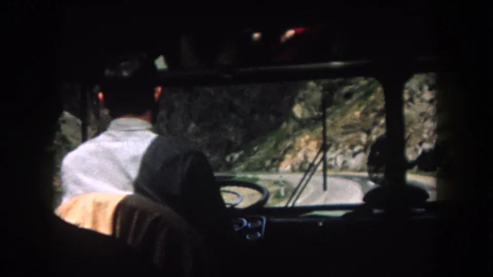 Backseat view of a man driving on a narrow mountain road in Summit County, Colorado, in 1962 home-movie footage.