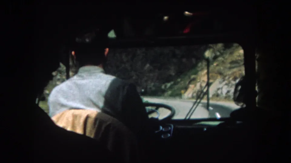 Interior vehicle view of a driver on a narrow Summit County mountain road, with rocks and vegetation beyond the windshield.