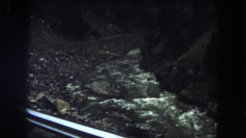 1962 8mm view of a fast river running through a rocky canyon in Summit County, Colorado, with a rail crossing the foreground.