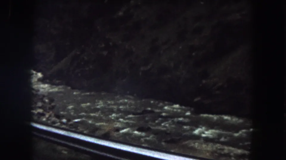 Dim 8mm frame of a mountain creek or river in Summit County, Colorado, filmed from a moving vehicle in 1962.